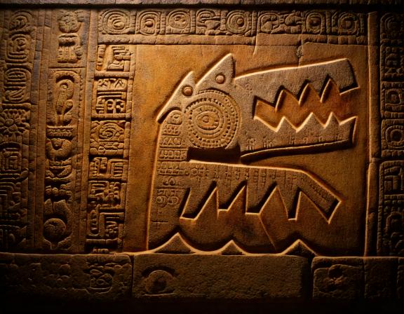 An ancient Mayan tablet with intricate patterns and glyphs surrounding a
                    Crocoduck-like figure in a small pool, its wings outstretched.